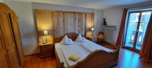 1 dormitorio con 1 cama con sábanas y almohadas blancas en Zum Heisn en Lenggries