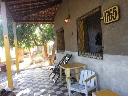 un patio avec des chaises et une table ainsi qu'un panneau sur un bâtiment dans l'établissement Casa de praia rústica, à Luis Correia