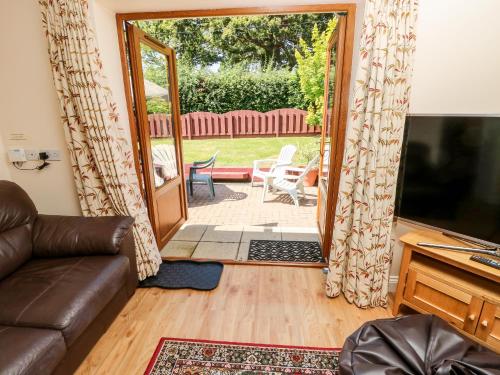 a living room with a couch and a sliding glass door at 1 The Stables in Haven Street