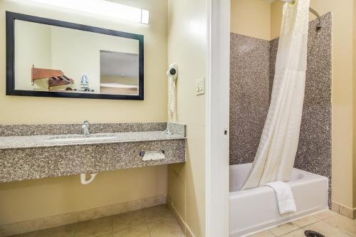 a bathroom with a sink and a tub and a mirror at Americas Best Value Inn & Suites Tomball in Tomball