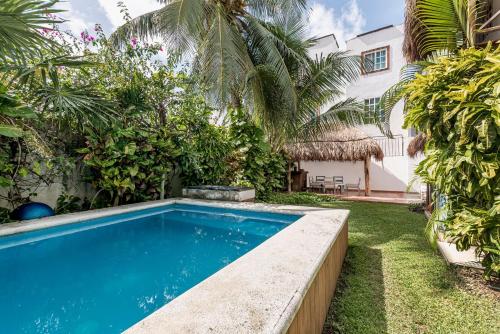 a swimming pool in front of a house with palm trees at Casa Nona Azul in Cancún