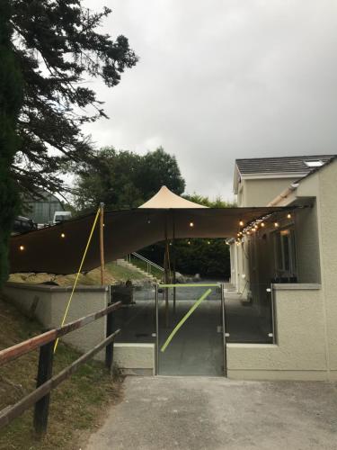 a patio with an umbrella in front of a house at Rostrevor Mountain Lodge - Glamping Pods - Revive Sauna & Hot Tubs in Rostrevor