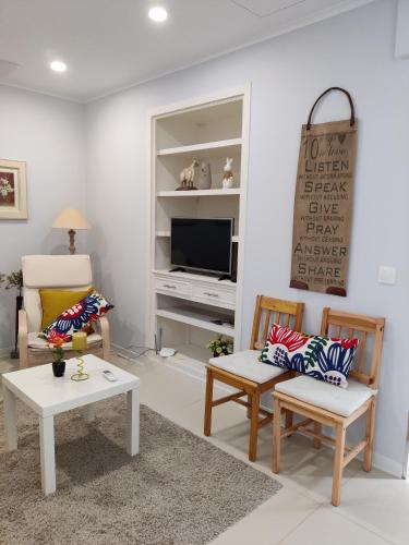 a living room with two chairs and a tv at Long Beach Apartamento AL in Praia da Vitória