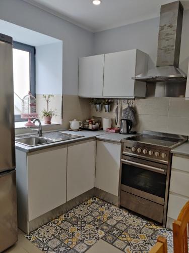 a kitchen with white cabinets and a sink and a stove at Long Beach Apartamento AL in Praia da Vitória