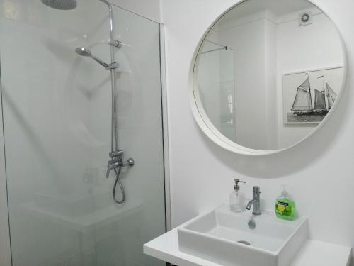 a white bathroom with a sink and a mirror at House with a view in Alcácer do Sal
