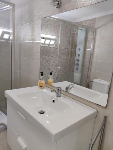 a bathroom with a white sink and a mirror at Long Beach Apartamento AL in Praia da Vitória