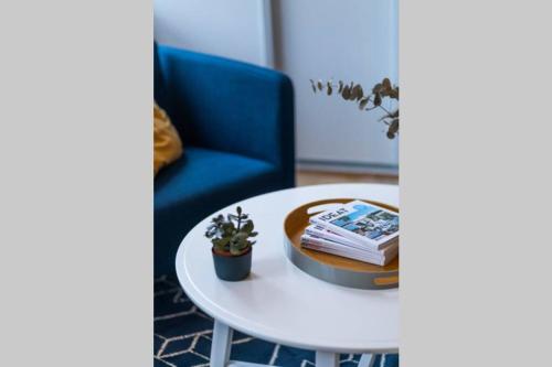 a coffee table with books and a blue chair at L'inattendu/Studio équipé et confortable in Fontenay-le-Comte