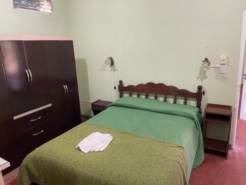 a bedroom with a bed with a green blanket and a dresser at Naturaleza Pura Casa La Caldera in Salta