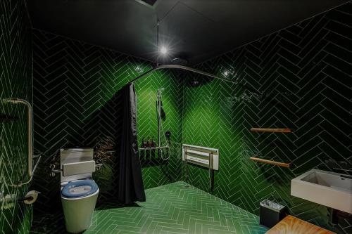 a green bathroom with a toilet and a sink at Moss Hotel in Hobart
