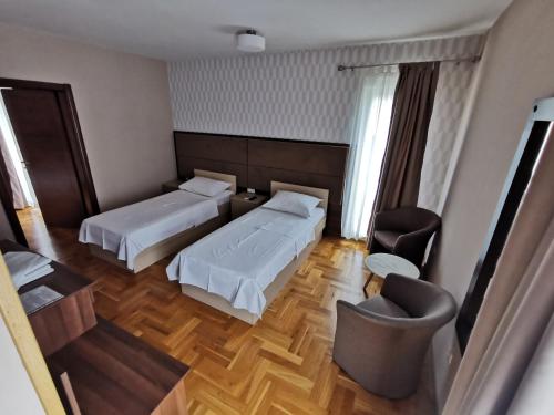 a hotel room with two beds and a chair at Villa Salvia in Mostar