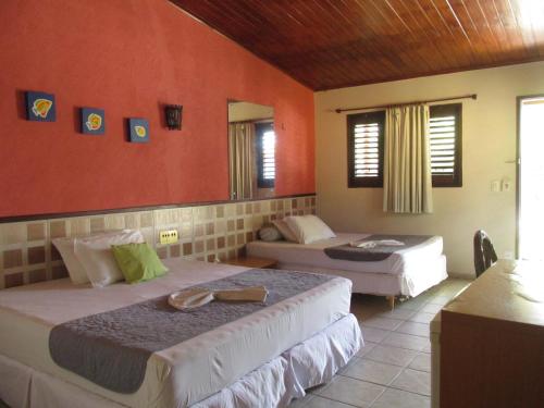 two beds in a room with red walls at Hotel Enseada Maracajaú in Maracajaú