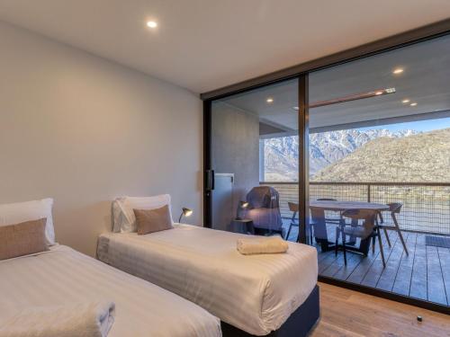 two beds in a room with a table and a balcony at The Bunker Bravo A in Queenstown