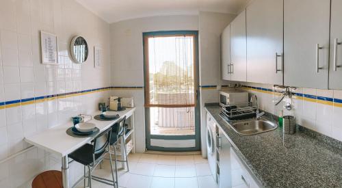Una pequeña cocina con fregadero y ventana. en Beach House Carmen, en Monte Gordo