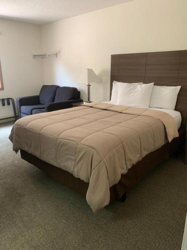 a bedroom with a large bed and a blue chair at Lakes Area Inn 