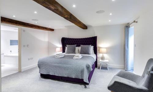 a bedroom with a large bed and a chair at The Shippon Cottage in Kendal