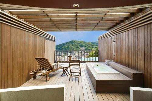 a bathroom with a tub and two chairs and a table at Relax Resort Hotel in Atami