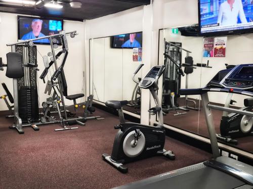 a gym with several tread machines and televisions at Burke and Wills Hotel Toowoomba in Toowoomba