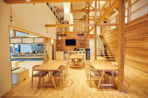 un comedor con mesas de madera y una escalera en ゲストハウス酒坊多満自慢 en Fussa