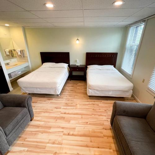 Cette chambre comprend deux lits et un canapé. dans l'établissement Baseball Town Motel, à Cooperstown