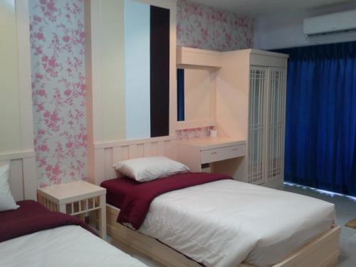 a bedroom with two beds and a window at Tokyo Country Inn in Nakhon Ratchasima