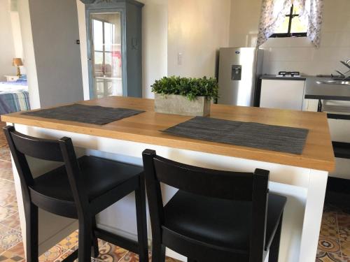 cocina con encimera de madera y 2 sillas negras en ChulaVista Constanza Colonial Suite, en Constanza