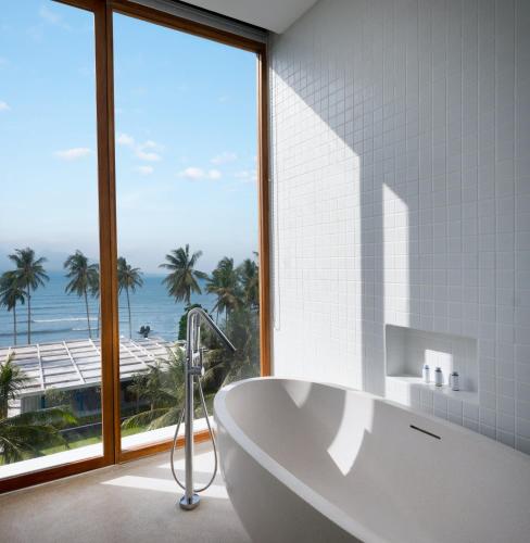 a bathroom with a tub and a large window at Dialoog Banyuwangi in Banyuwangi