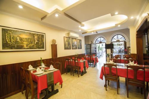 un restaurant avec des tables et des chaises rouges et une peinture murale dans l'établissement Reaksmey Chanreas Hotel, à Siem Reap