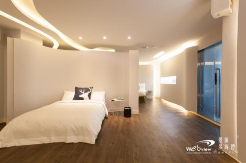 a bedroom with a white bed and a wooden floor at Ya Nold Hot Spring Hotel in Jiaoxi