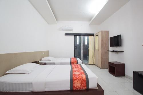 a bedroom with two beds and a flat screen tv at Adikara Renon in Denpasar