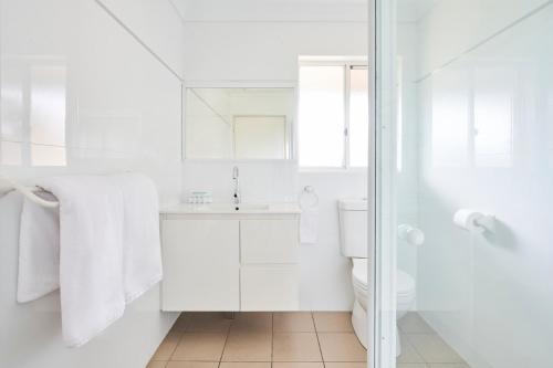 a white bathroom with a sink and a toilet at Harbourview House in Bermagui