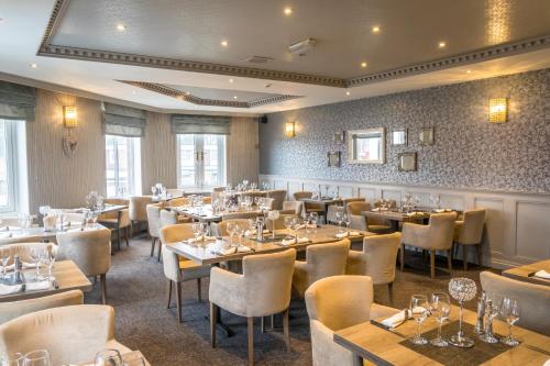 a restaurant with tables and chairs in a room at Washington Central Hotel and Sleepwell Inn in Workington
