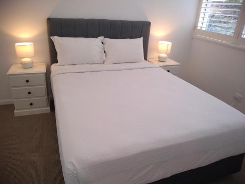 a white bed with a white comforter and pillows at Chasely Apartment Hotel in Brisbane