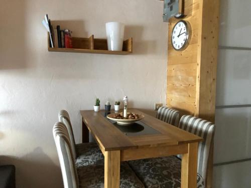 une table en bois avec des chaises et une horloge sur le mur dans l'établissement Aiguille du Midi - Le Chamo'nid, à Chamonix-Mont-Blanc