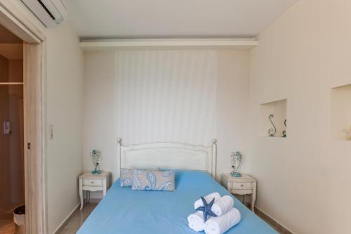 a bedroom with a blue bed with towels on it at Villa Nostalgia Lentas No4 in Léntas