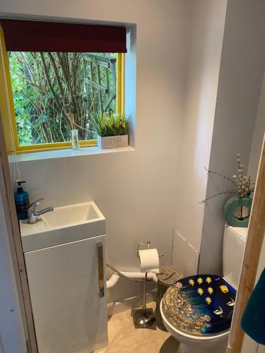 a bathroom with a sink and a toilet and a window at Pet Friendly Dairy Cottage in Solihull