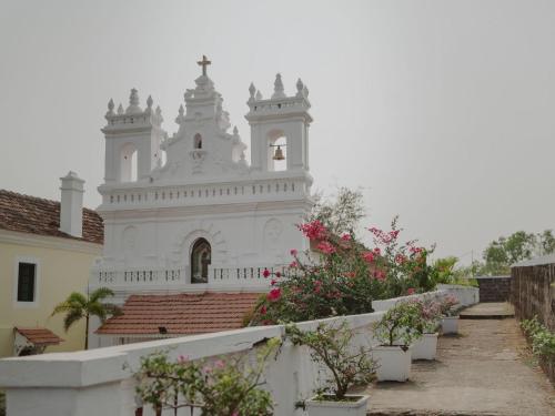 a white church with a steeple on top of a building at Fort Tiracol Goa in Arambol
