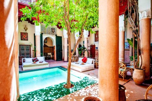 una piscina en un patio con árboles y sillas en Riad Chorfa, en Marrakech