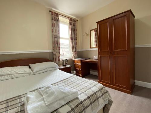 a bedroom with a bed and a cabinet and a window at Kings Arms Hotel in Lockerbie
