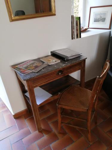 a desk with a laptop on top of it with a chair at La Maison des Rosiers in Manhac