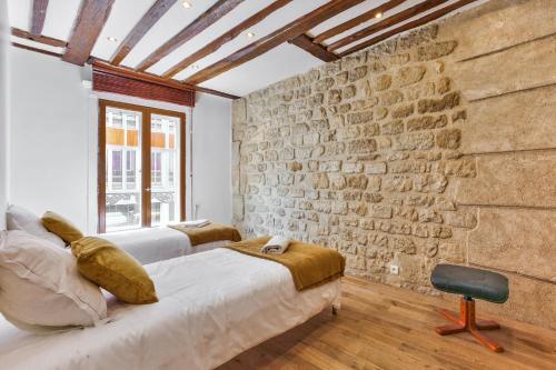 a bedroom with two beds and a brick wall at 43- Parisien Flat Boulevards in Paris