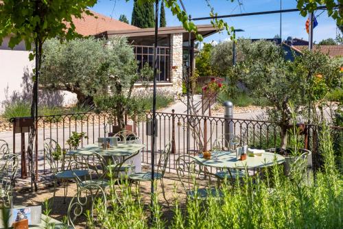 two tables and chairs in front of a fence at Terre de Provence Hôtel & Spa in Le Pontet