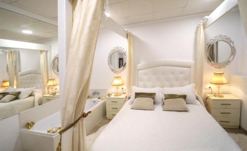 a white bedroom with a bed and a tub and mirrors at Apartamento Romero Garden B in Villanueva de Arosa