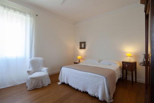 a white bedroom with a bed and a white chair at La mia casa a Levante in La Spezia