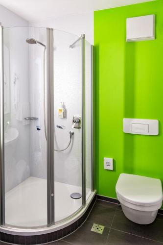 a green bathroom with a shower and a toilet at Akzent Hotel Restaurant Hirsch in Heidenheim