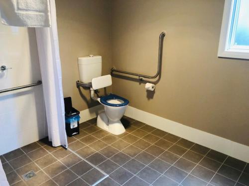 a bathroom with a toilet with a blue seat at Huskisson Beach Escape in Huskisson