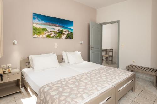 a white bedroom with a large bed and a table at Niriis Hotel in Kato Daratso