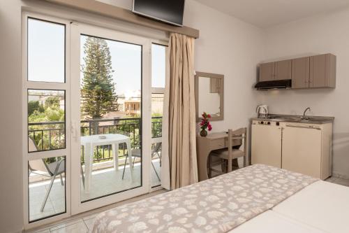 a bedroom with a bed and a kitchen with a balcony at Niriis Hotel in Kato Daratso