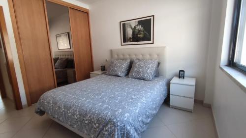 a bedroom with a bed with a blue blanket and pillows at Appartement Quinta de Palames Sesimbra in Sesimbra