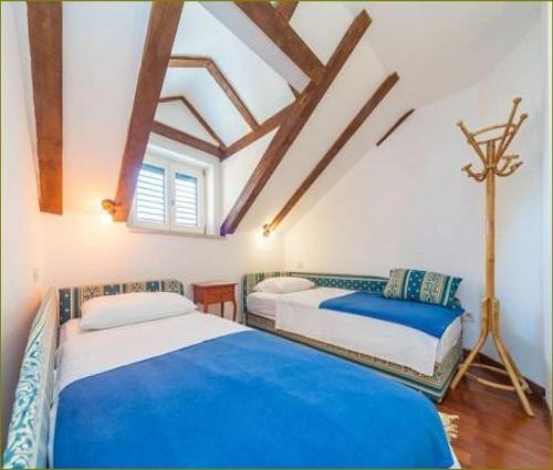 two beds in a room with wooden ceilings at Apartments Vi-La in Dubrovnik
