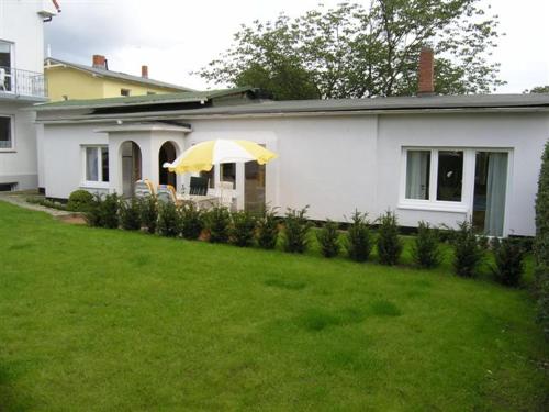 a white house with an umbrella in a yard at Ferienhaus Friedrich-Borge-Straße in Kühlungsborn